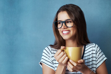 Woman, student and coffee in studio with thinking, drink and glasses on blue background. Smile, caffeine or energy or mockup for learner person, hands and matcha or green tea for hydration and relax