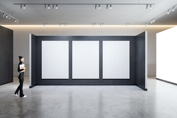 A person standing in a gallery with three empty frames on a wall, modern spacious interior design