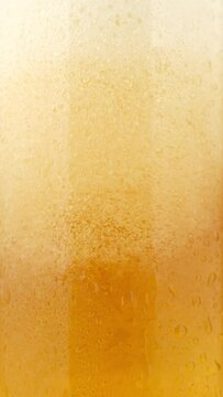 Cold beer with foam pouring in glass, macro