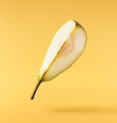 Fresh ripe Pear falling in the air, isolated on yellow background. Food levitation or zero gravity concept. High resolution image