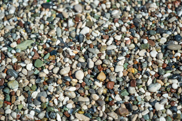 Beach with multicolored small round stones on a sunny day