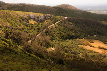 Fototapeta premium Impressive view of a mountain range with forest and road in soft sunlight. High quality detailed stock photo