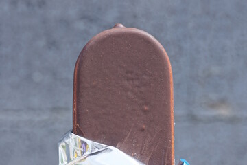 one big ice cream in chocolate on the background of the gray wall