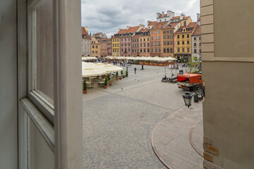 View of Warsaw's vibrant town square, filled with colorful buildings and outdoor cafes, captured...