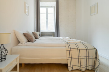 A bright and airy bedroom with a large window, featuring a comfortable bed with soft pillows and a...