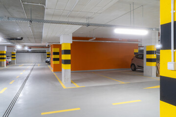 A modern underground parking garage featuring bright lighting, clear markings, and yellow-black...