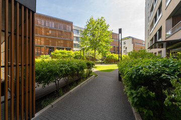 A modern residential complex featuring sleek buildings with wooden accents, greenery and...