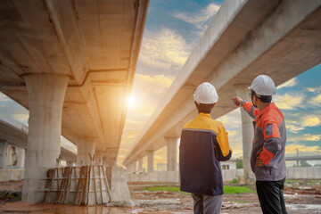 A team of civil engineers with architects and industrial construction workers on road construction site. Engineer team concept.	