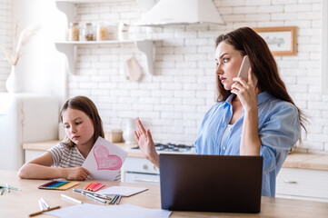 Bored sad little daughter waiting for mother while woman have important call a