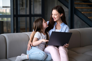 Mother and daughter using modern netbook for online study, watching educational content