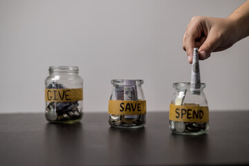 Give, Save, Spend money jars. She organized her finances into three jars labeled Give, Save and Spend, ensuring a balanced approach to managing her money. words, lettering, donate, jar, money.