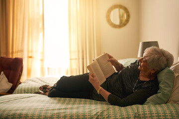 Elderly woman, book and reading on bed for retirement with smile, wellness and learning for...