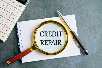 Business concept. The inscription - CREDIT REPAIR through a magnifying glass on a notebook in a...
