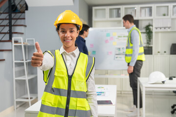 Portrait of confident female engineer standing and holding tablet at construction office. Woman foreman wearing vest and hardhat safety ready to team