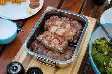 Gegrilltes Steak und Schweinefleisch in Alutasse am Tisch