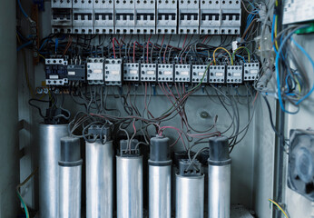 Detail of a capacitor bank with cables, fuses and other electrical components in a workshop.