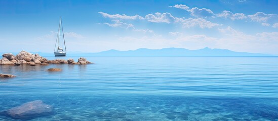 A solitary sailboat near a stunning reef in crystal-clear waters with a vast expanse of unoccupied space for text or design, known as copy space image.