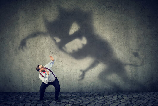 Business man scared by his monster shadowBusiness man scared by his monster shadow