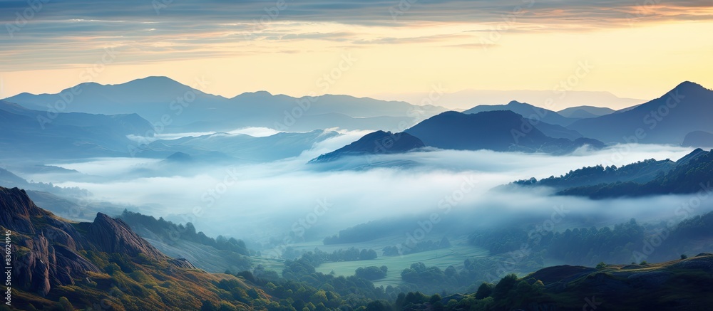 Poster Mountain landscape at dawn with misty clouds and rocks in the foreground, perfect for a copy space image.