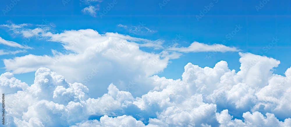 Poster Fluffy white clouds against a clear blue sky, creating a soothing backdrop with copy space image.