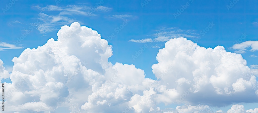 Poster fluffy white clouds dotting the clear blue sky offer a serene view for a copy space image.