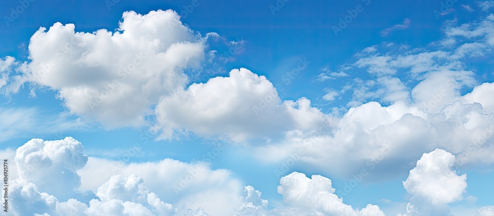 Poster background of a clear blue sky dotted with small fluffy clouds offers ample copy space image.