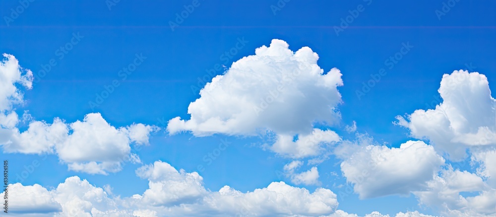 Poster background of a clear blue sky dotted with small fluffy clouds offers ample copy space image.