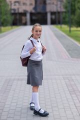Portrait of caucasian schoolgirl in uniform and with backpack outdoors. 