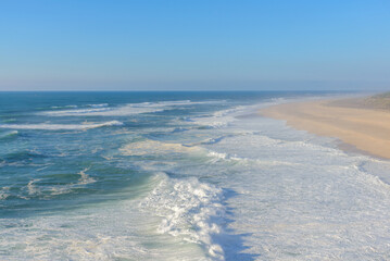 Aerial view of sandy beach and Atlantic ocean with big waves in Nazare, Portugal. Surfing paradise town in Portugal, Europe