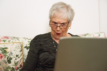 Senior woman, shock and laptop in house with internet for watch film, social media and streaming...