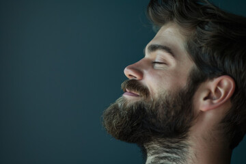 Obraz premium A close up of a man with beard and closed eyes looking to a side