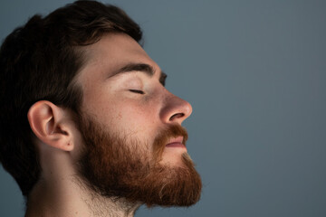 Obraz premium A close up of a man with beard and closed eyes looking to a side
