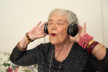 Senior woman, relax and headphones in house with music for retirement, audio playlist and streaming...