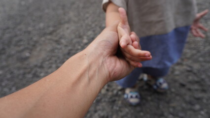 A harmonious family scene depicting a loving father holding his small and cute child's hand. The...