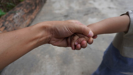 A harmonious family scene depicting a loving father holding his small and cute child's hand. The...