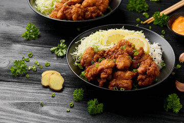 Japanese Fried crispy Chicken Karaage in black bowl with rice and cabbage