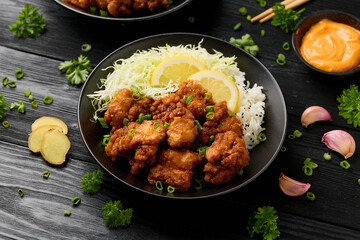 Japanese Fried crispy Chicken Karaage in black bowl with rice and cabbage