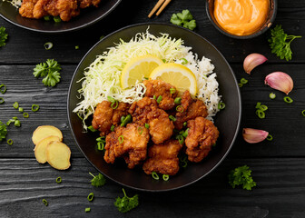 Japanese Fried crispy Chicken Karaage in black bowl with rice and cabbage