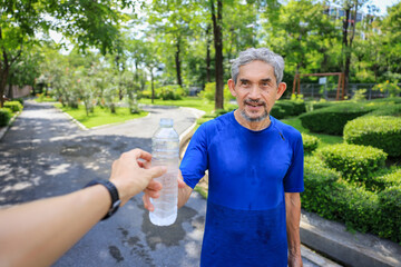 Senior Asian man is drinking water after morning exercise in the park for rehydration of sweat loss...