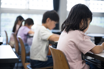 No face in profile of elementary school students studying in a bright classroom Plural people For the image of children taking exams, cramming, and studying at school.