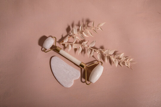 Tool for massage roller made of jade and guash on a peach background. Anti-aging and lifting effect at home. Facial care device and relaxation concept.