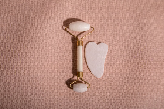 Massage with a face roller with white natural jade. Tool for massage guash, with whey for beauty. Anti-aging and lifting effect at home. Facial care device and relaxation concept.