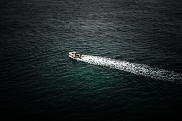 Naklejka premium Boat sailing on Atlantic ocean and leaving white trail. Selective focus. Travel concept
