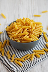 Raw Organic Dry Penne Pasta in a Bowl, side view.
