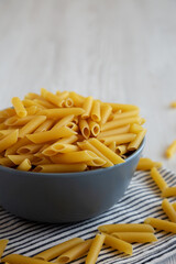 Raw Organic Dry Penne Pasta in a Bowl, side view.