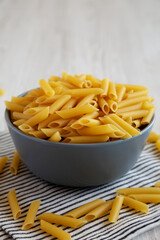Raw Organic Dry Penne Pasta in a Bowl, side view.