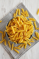 Raw Organic Dry Penne Pasta in a Bowl, top view.