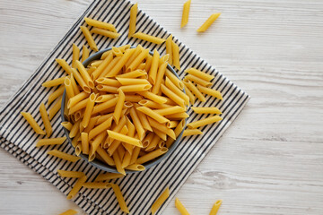 Raw Organic Dry Penne Pasta in a Bowl, top view. Copy space.
