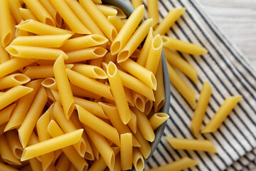 Raw Organic Dry Penne Pasta in a Bowl, top view. Overhead, flat lay, from above.