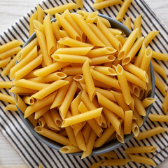 Raw Organic Dry Penne Pasta in a Bowl, top view. Overhead, flat lay, from above.